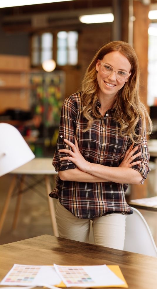 Women in a plaid shirt standing over a desk in a marketing department