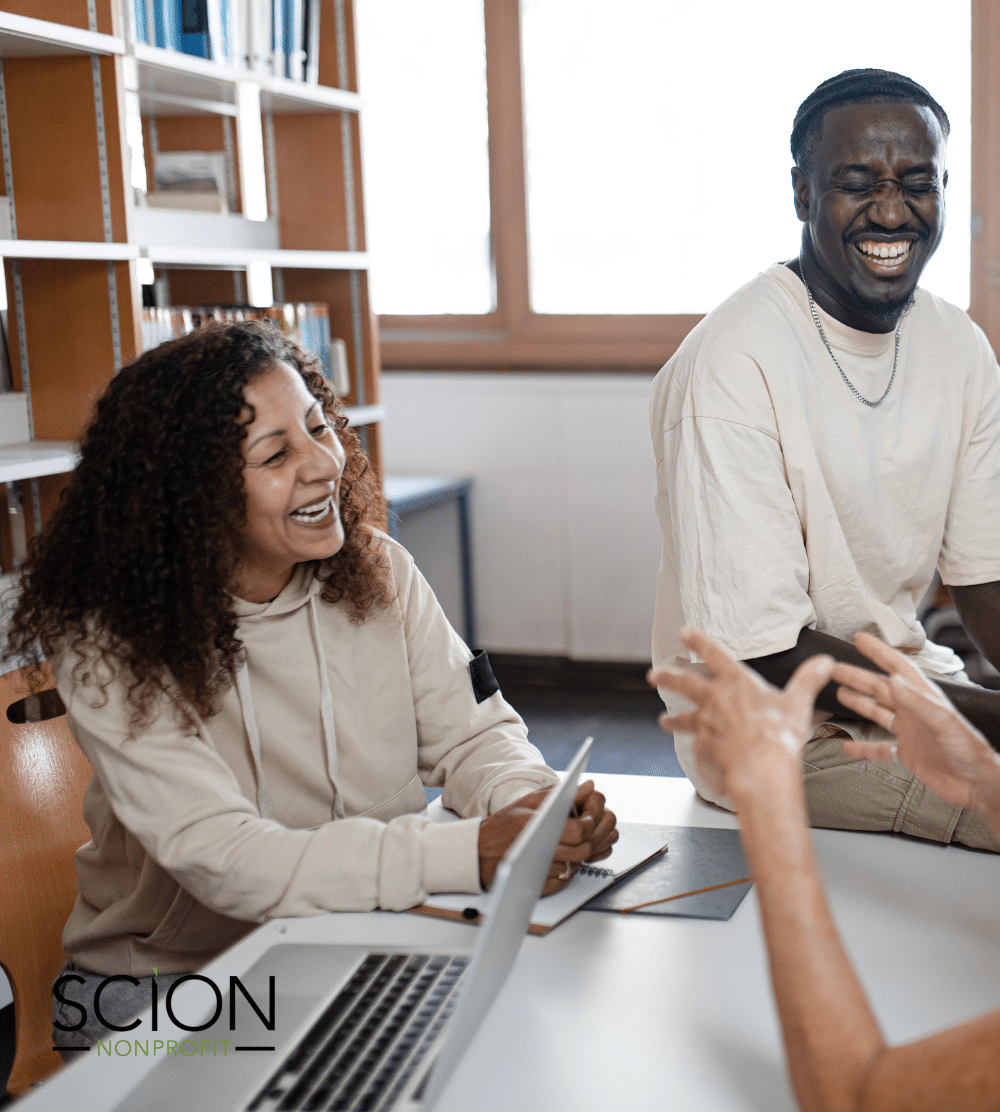 How Nonprofits Can Utilize Salary Guides to their Advantage - image of diverse nonprofit organization team at a table sharing a laugh during a discussion about salary guides